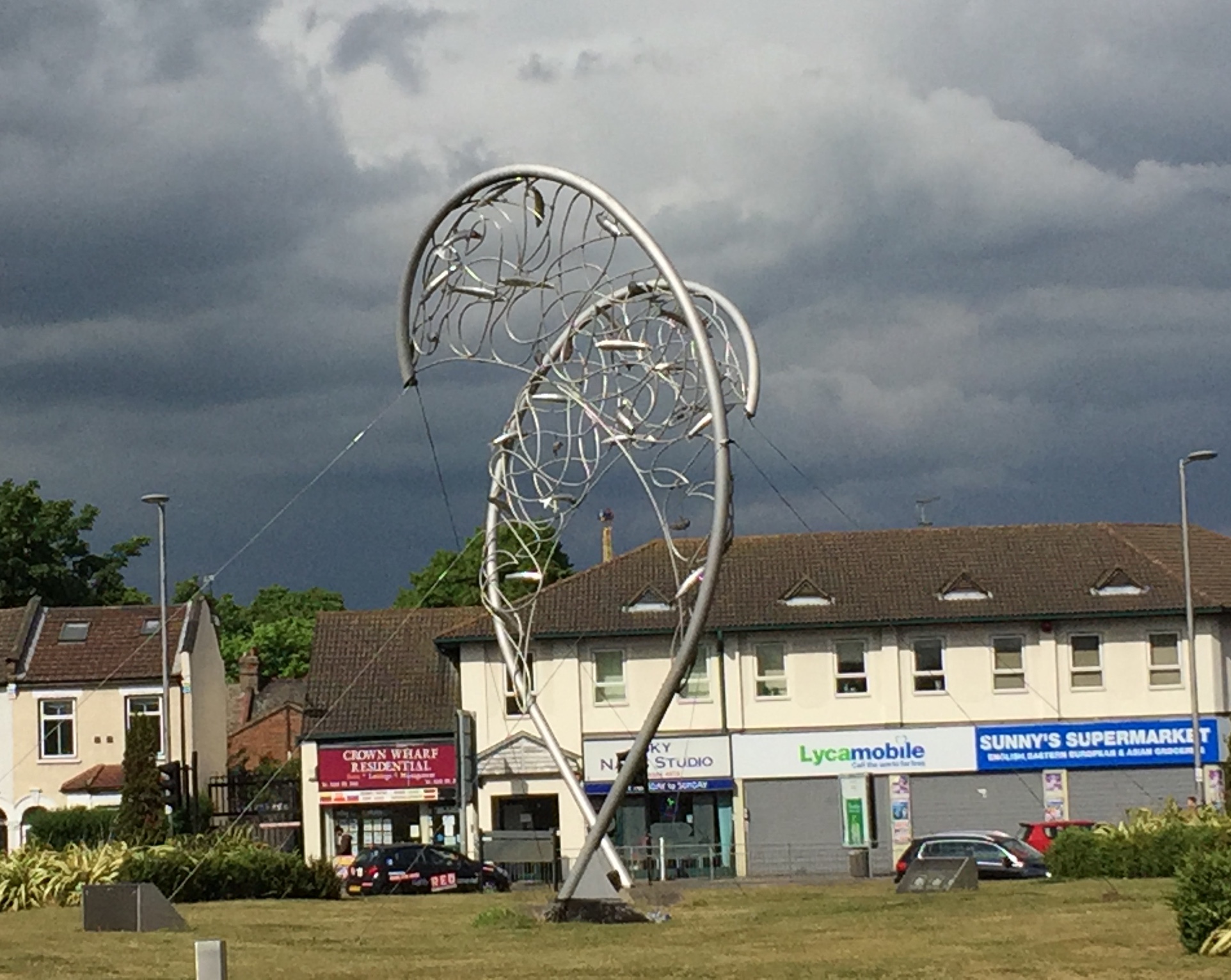 A tall metal sculpture called The Catch, showing the outline shape of a fish with curving pieces of metal inside it.
