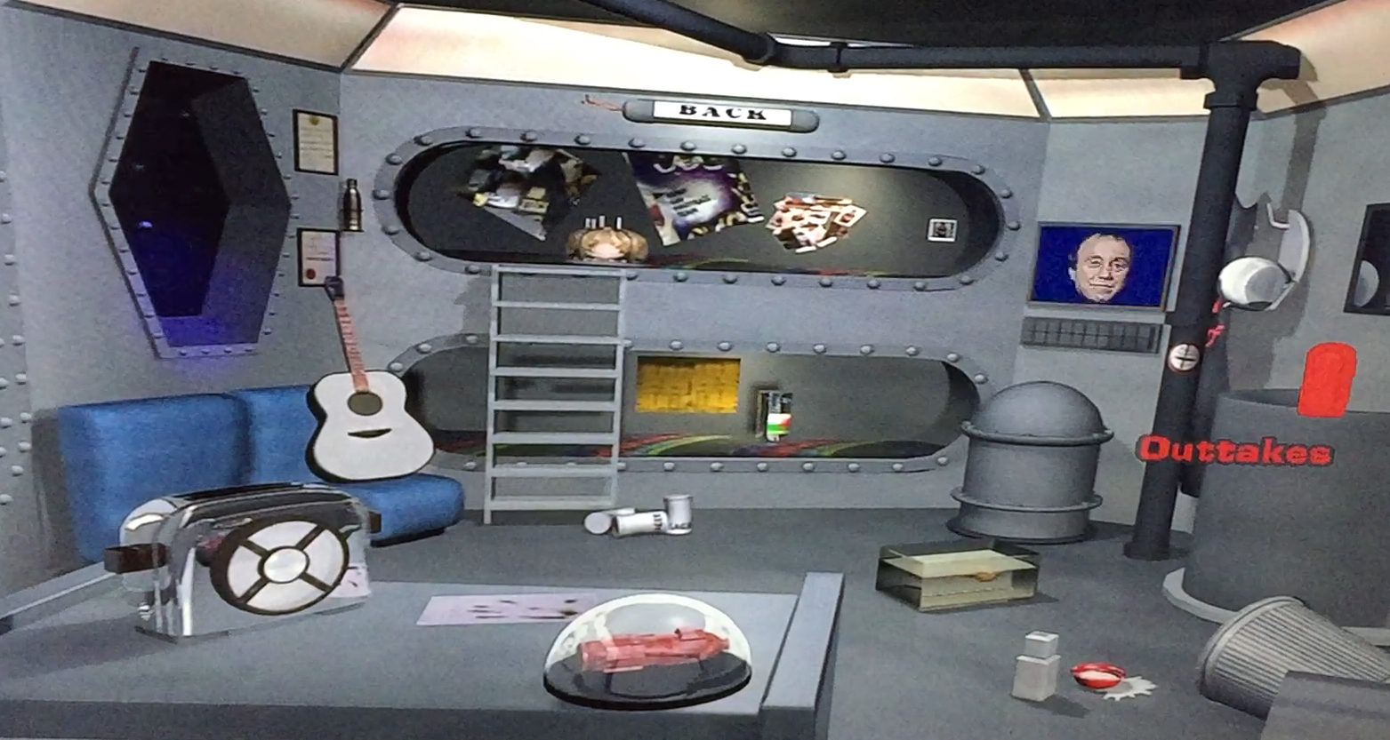The extras DVD menu for Red Dwarf series 1. The screen shows the bunk room where Lister and Rimmer sleep, and by moving around the screen you can select various items to access different features e.g. the guitar, toaster, model of the ship, computer screen, etc.