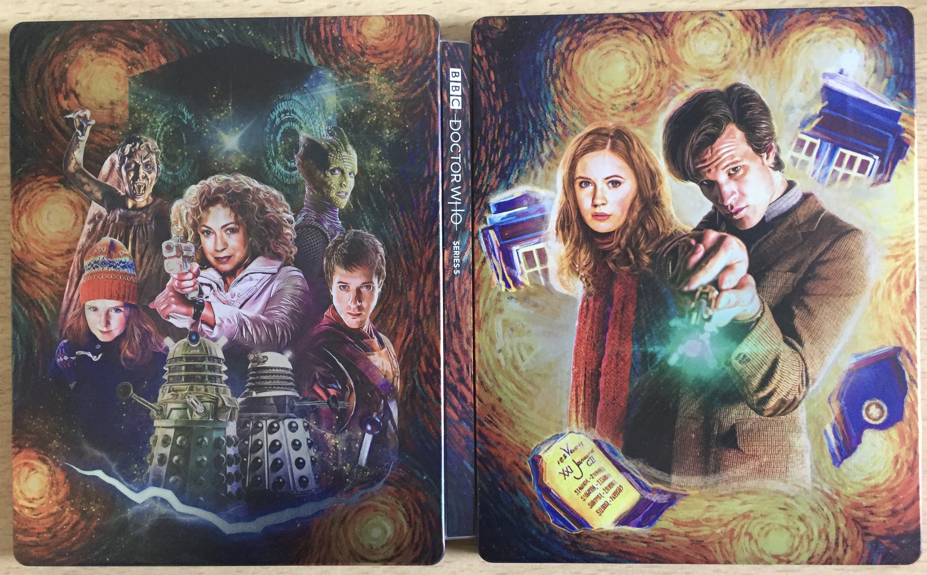 The unfolded cover of the Doctor Who Series 5 Blu-Ray Steelbook. The painted artwork shows The Doctor and Amy Pond on the right, with partial images of the Tardis swirling around them, while on the left is a selection of other characters, including Rory, River Song, young Amy and the Daleks.
