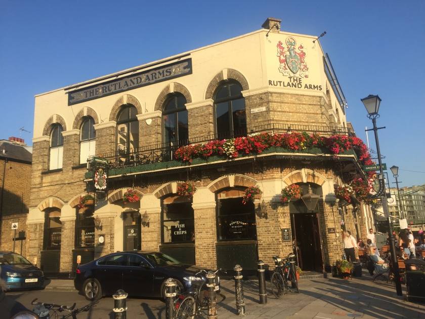 The Rutland Arms pub, a 2 storey building with brick arches over the windows and a first floor balcony adorned with colourful flowers.