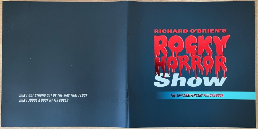 Cover spread for the Rocky Horror 40th anniversary photo book, with both the front and back covers having a black background. On the front, the words Rocky Horror in the title are written in blood red dripping letters. On the back, in smaller white text, are the song lyrics Don't get strung out by the way that I look, don't judge a book by its cover.