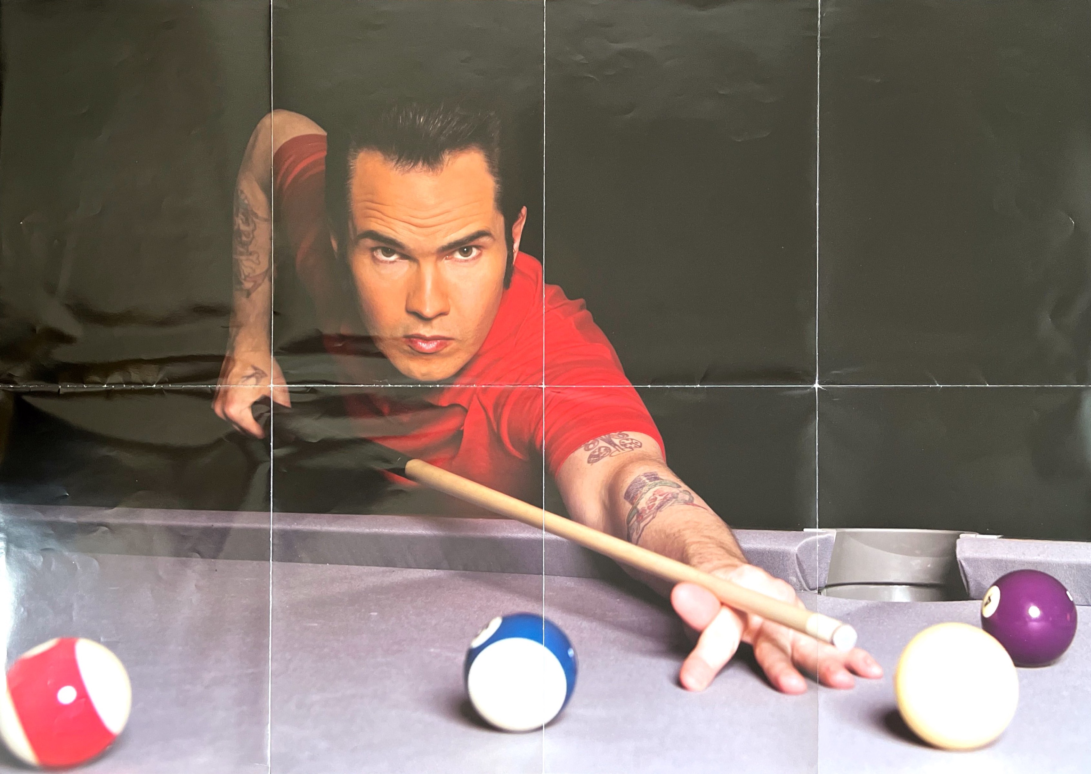 A large landscape poster, showing a photo of Jimmy Carr lining up a shot on a pool table.