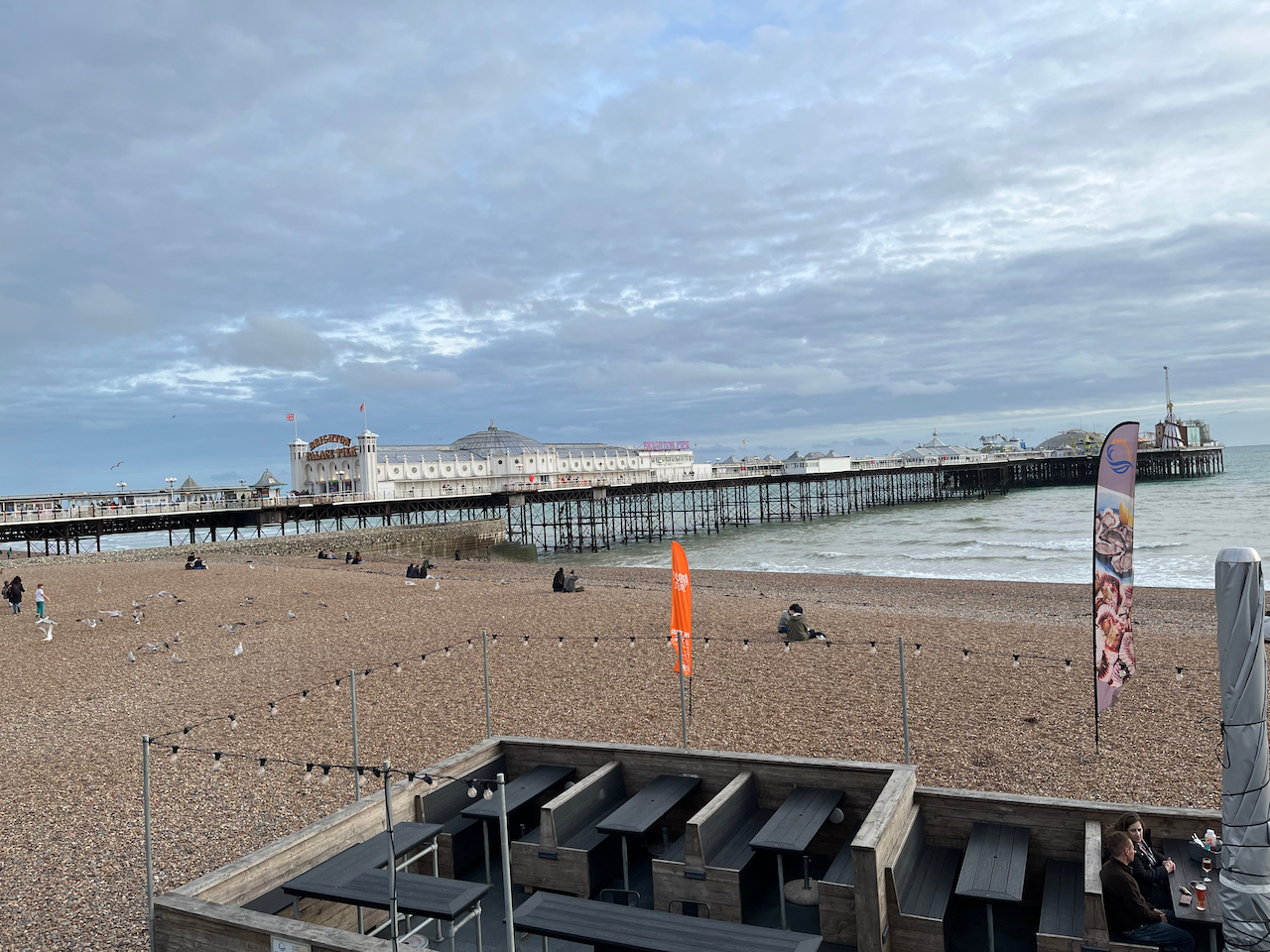 Brighton Palace Pier, with a long white building at the end near the shore, and lots of fairground attractions at the far end.