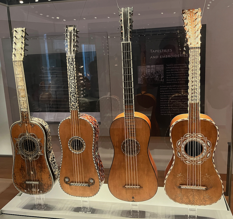 A display case containing 4 guitars, each decorated in a different way.