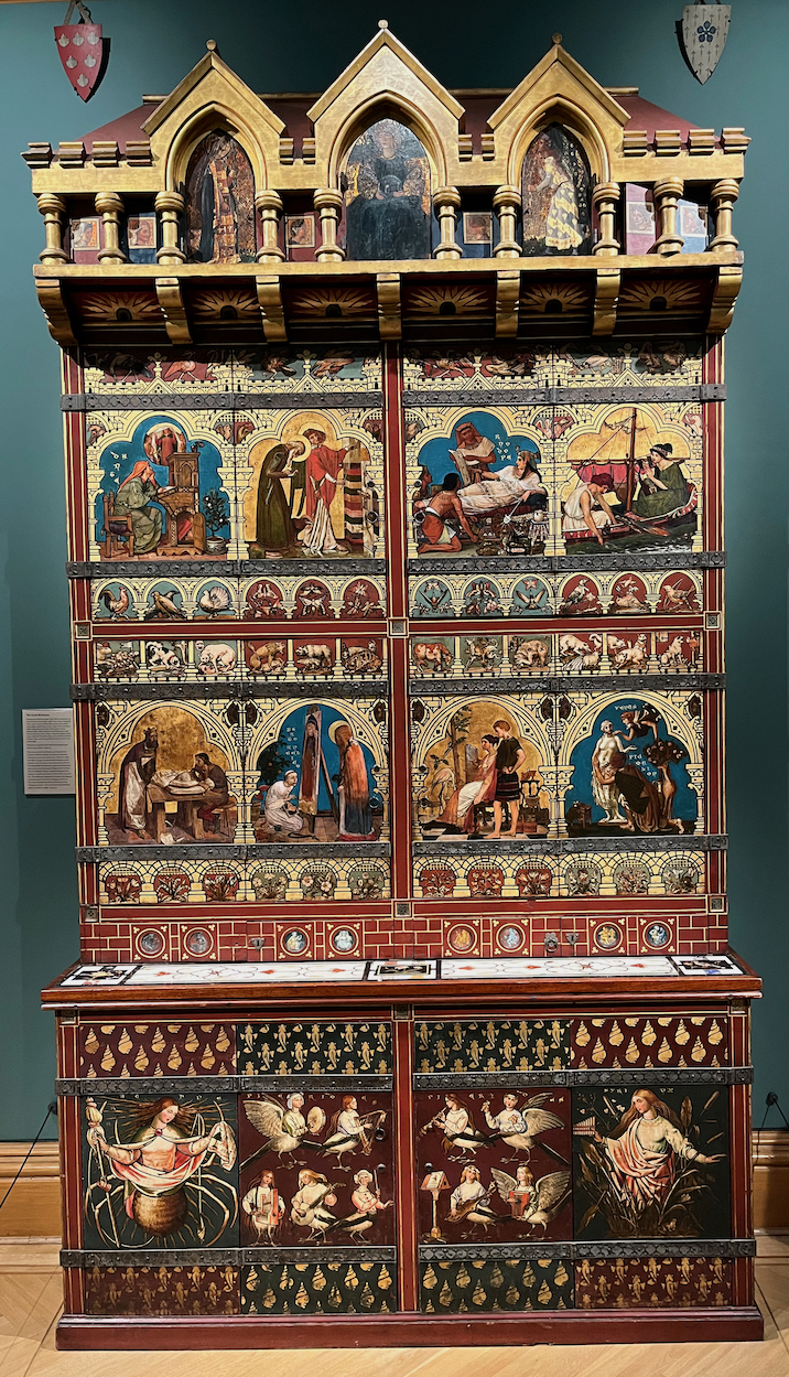 A huge and exquisitely decorated cabinet, with lots of colourful paintings in a variety of sizes.