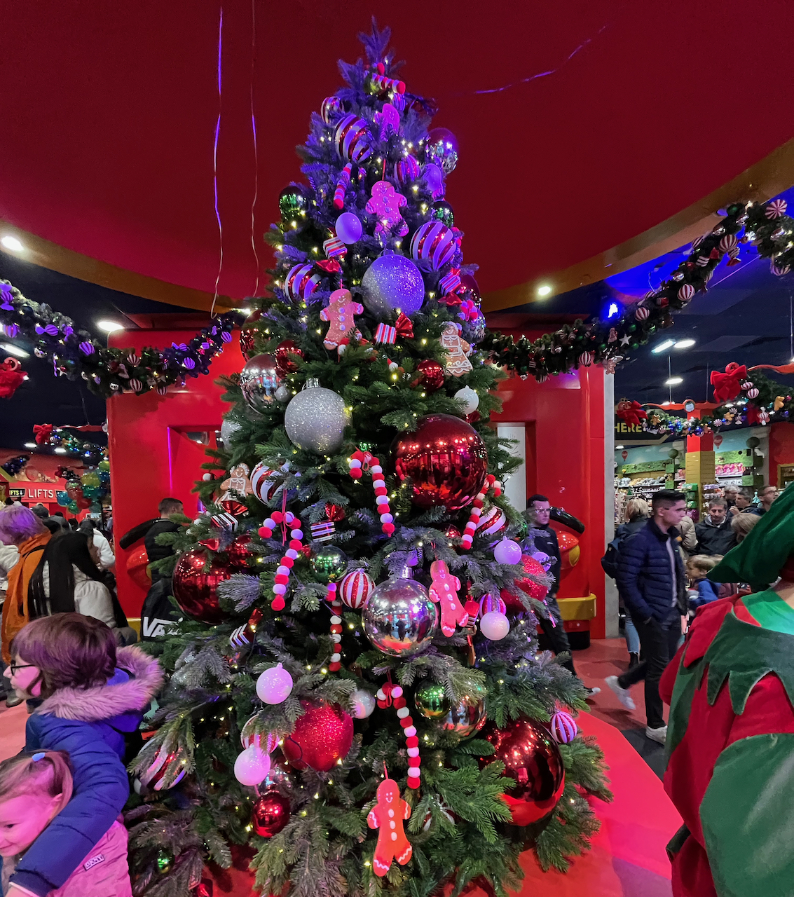 A large Christmas tree in Hamleys toy store, decorated with a variety of red, white and silver baubles, red and white striped candy canes, gingerbread men and lights.